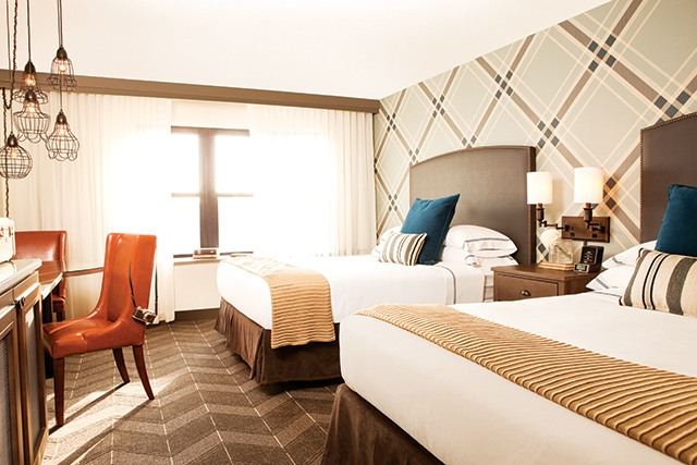 The geek-chic style of the hotel is ever-present in the guest rooms with a blue plaid accent wall. Photo courtesy of The Commons Hotel
