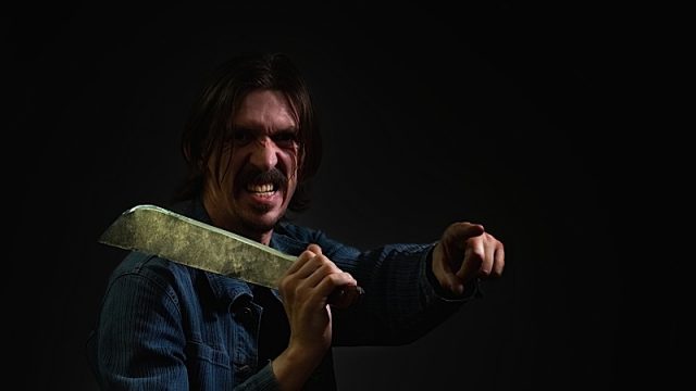 A Man Holds A Machete On His Shoulder And Points The Finger Of His Other Hand Forward. The Guy Is Vi Photo courtesy of BigStock/romsvetnik