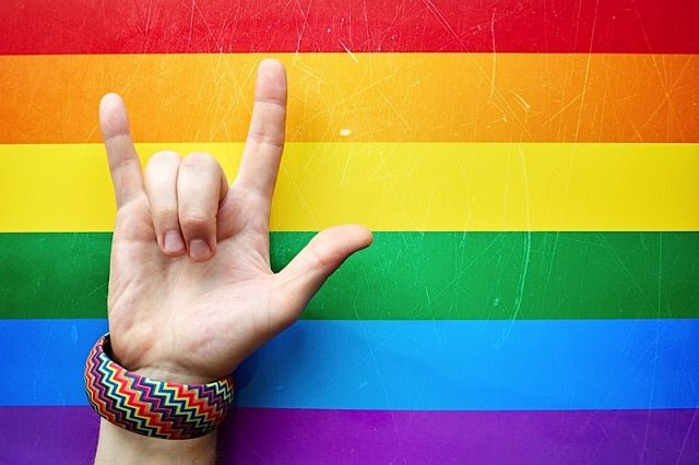 "i Love You" In American Sign Language (asl) Which Shows A Man's Hand On The Background Of The Flag Photo courtesy of BigStock/vkfoto