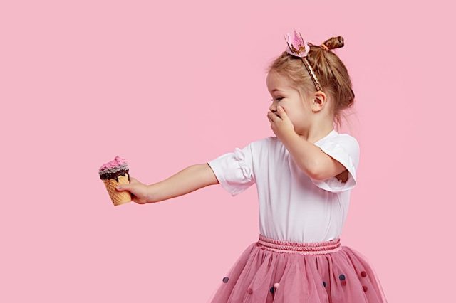 Cute Child Girl Holds Ice Cream On His Outstretched Arm And Covers His Mouth With His Hand. Refuses Photo courtesy of BigStock/shcherban
