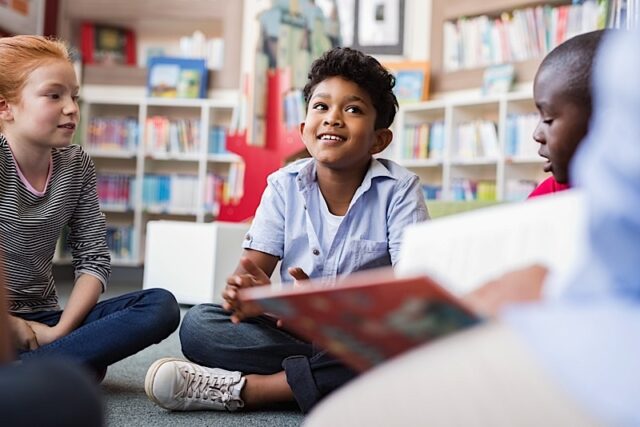 Happy young child in a reading circle at school or the library.
