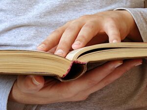 Hand resting on the pages of an open book.