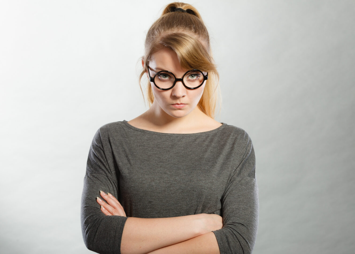 Young woman with crossed arms expressing rage, disgust and anger.