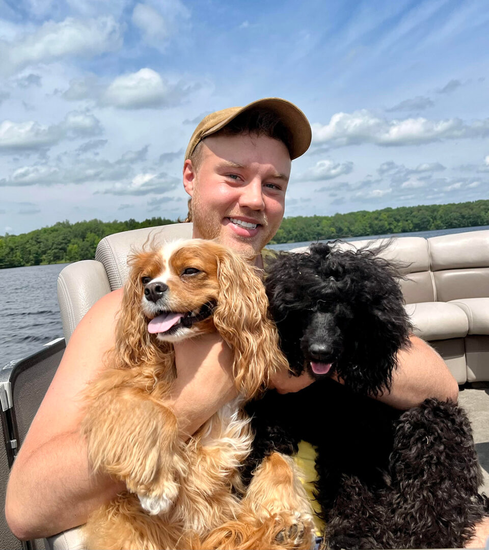 Jory Miller holding two small dogs on a boat.