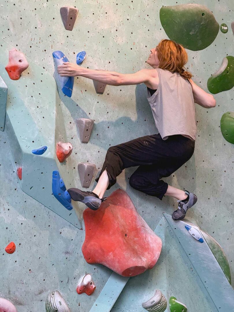 Ash climbing at an indoor rock climbing facility.