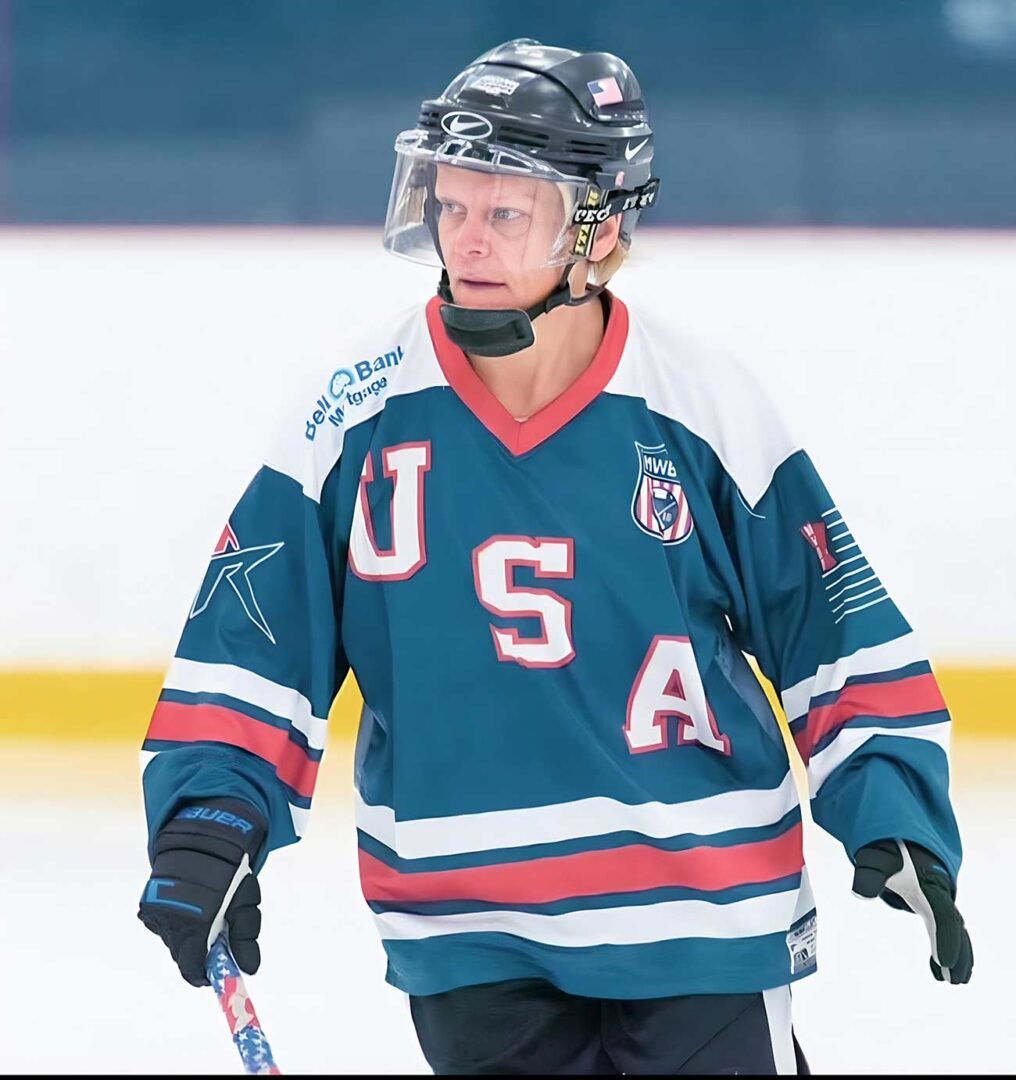 Woman in a USA jersey playing hockey.