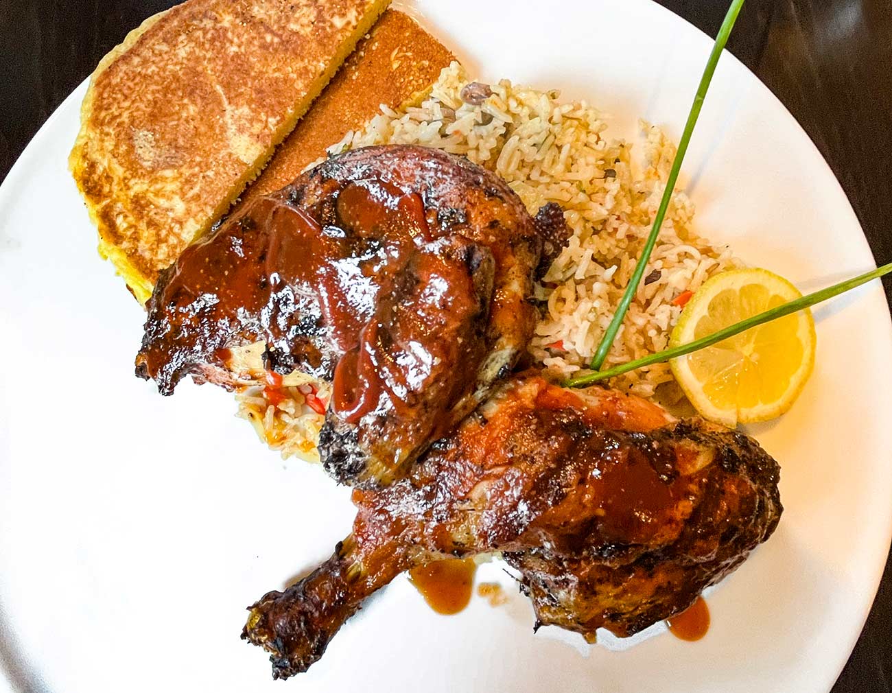 Plate with Jerk Chicken with rice and johnnycakes.