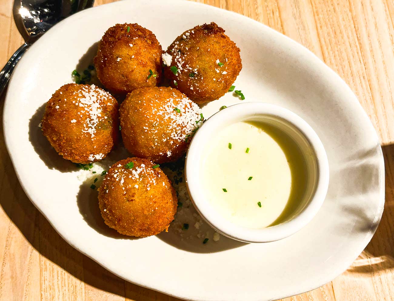 Small plate of Arancini balls with cheese sauce.