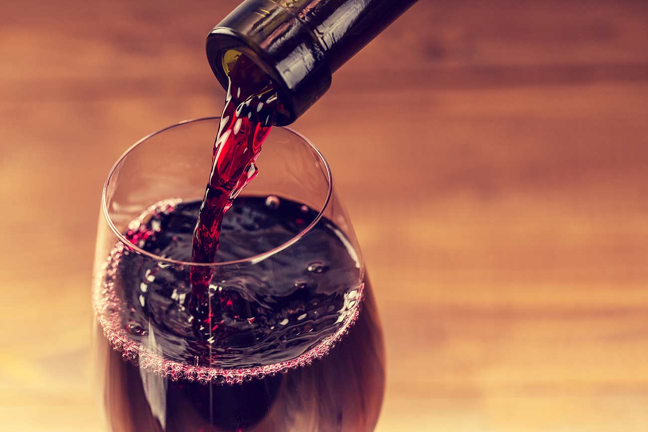 Pouring red wine into the glass.