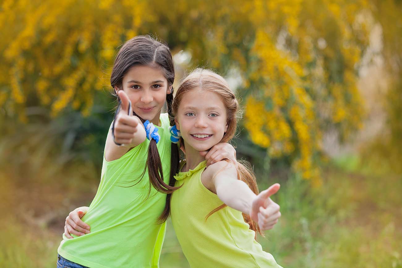 Happy diverse smiling kids at summer camp thumbs up.