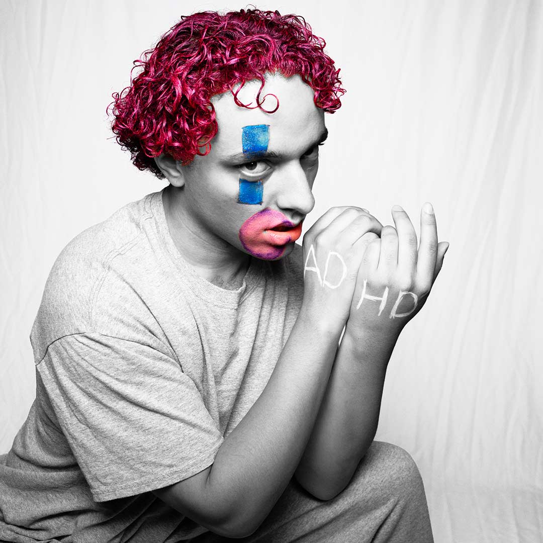Music artist posed in colored clown makeup for a promotional shot.