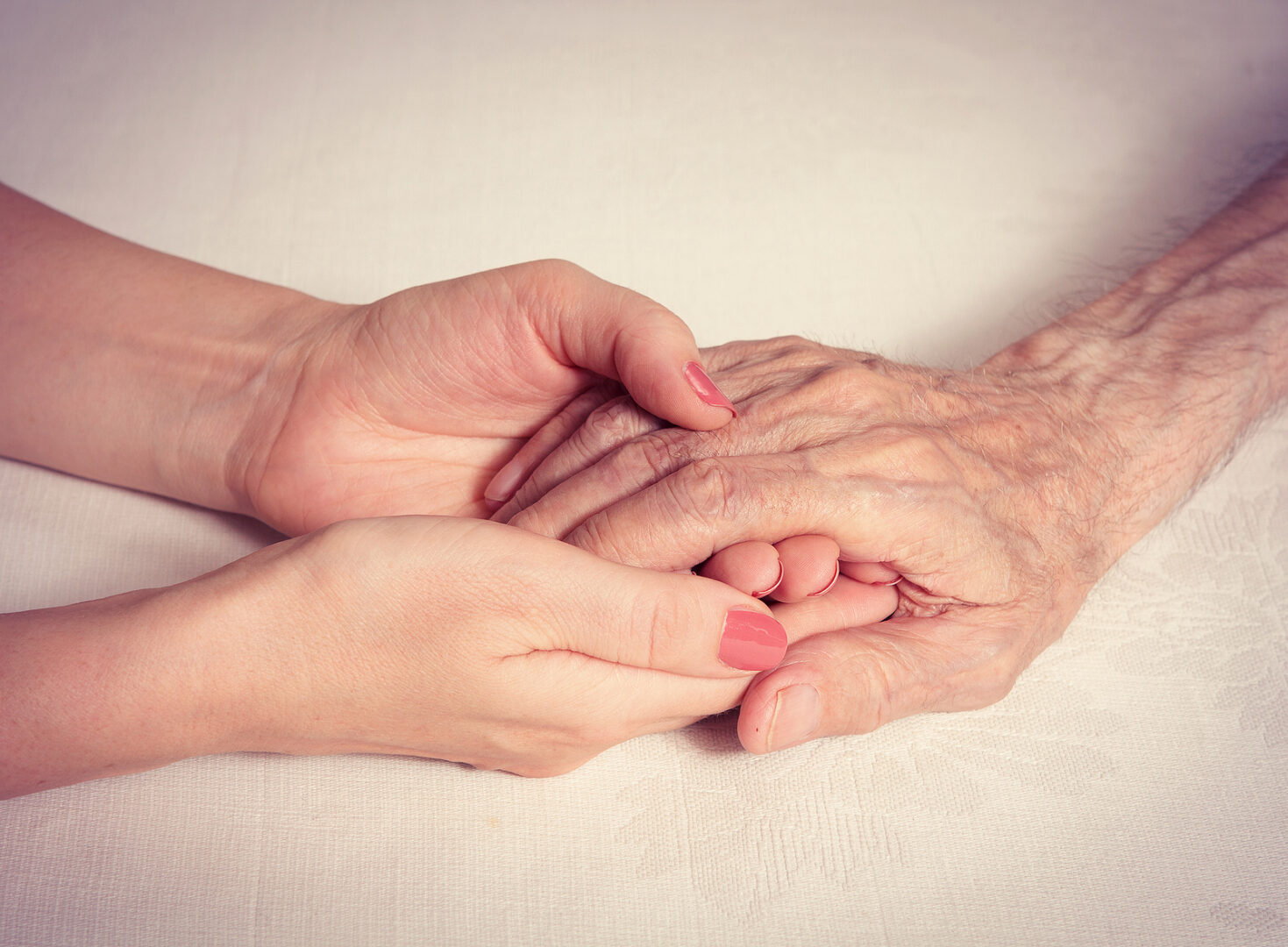 Caring hands holding the hand of an elderly person.