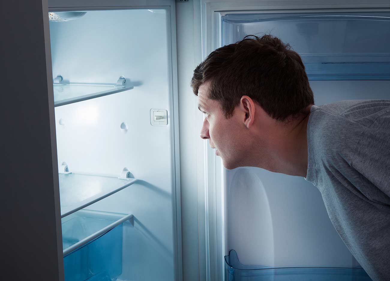 Portrait of a hungry man looking for food in refrigerator.