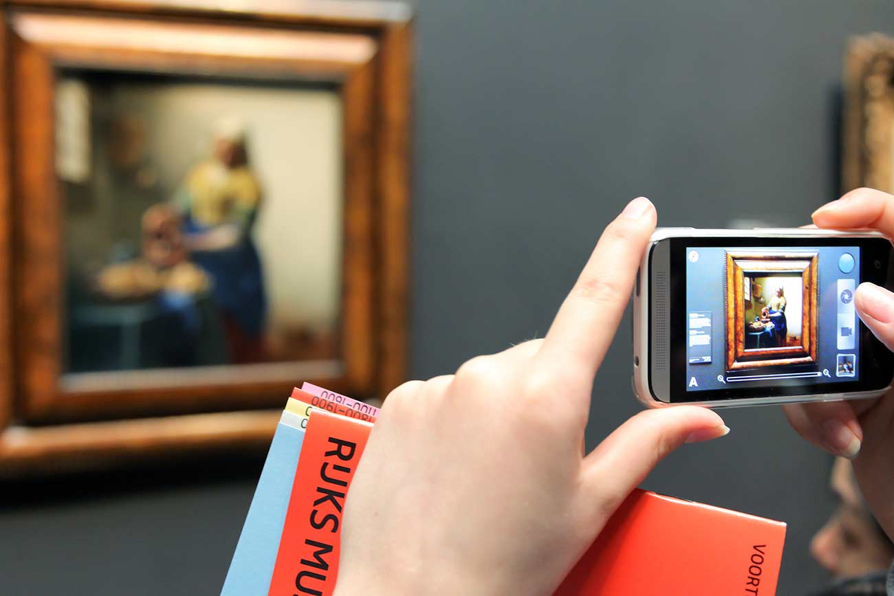 Person taking a photo of a famous painting.