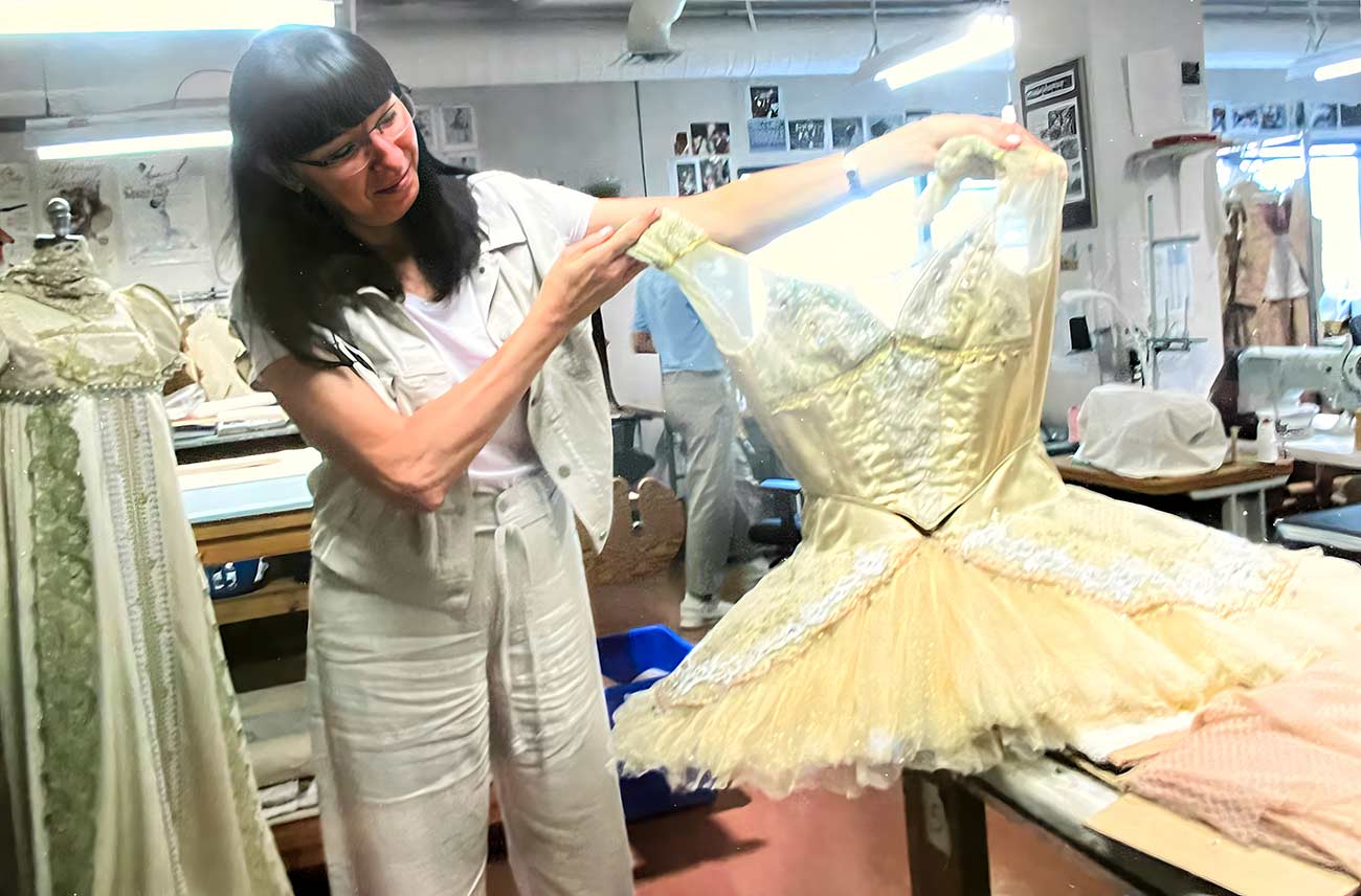 Woman holding up a costume at the costume shop at the Royal Winnipeg Ballet.