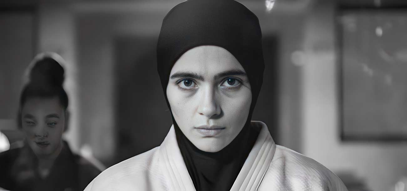 Black and white production still of a young woman staring into the camera lens in the film Tatami.