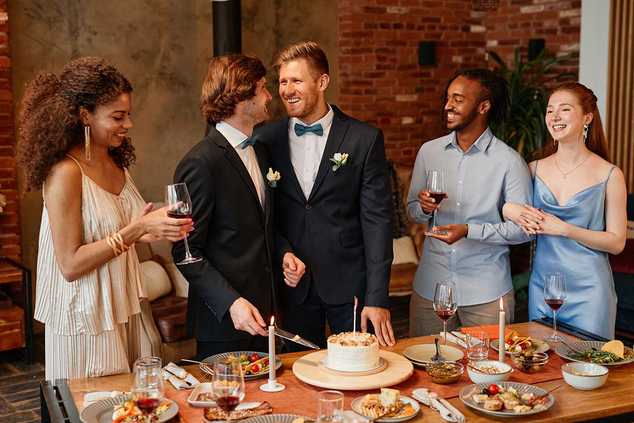 Young gay couple smiling happily while celebrating same sex marriage at wedding reception.