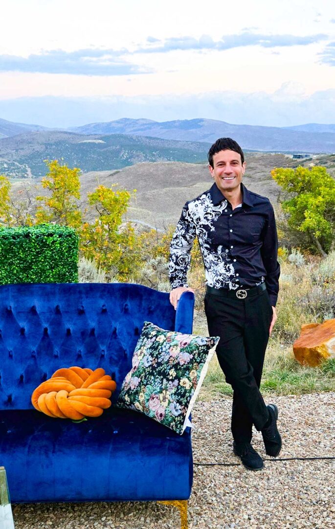 Joey poses next to a plush couch with the mountains in the background.