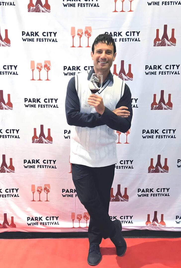 Joey standing in front of a step and repeat red carpet at the Park City Wine Festival.