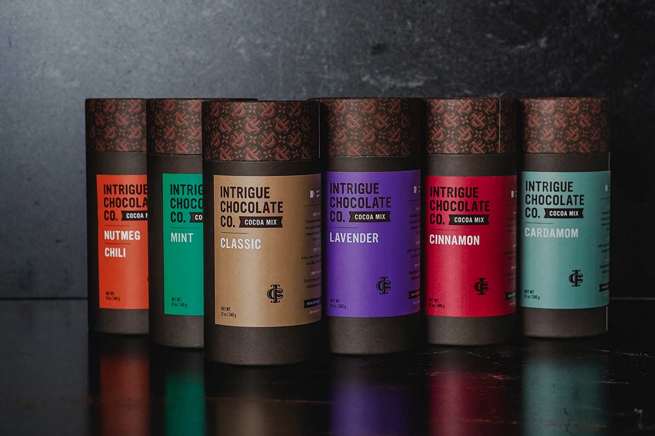 Six containers of different flavors of cocoa mix.