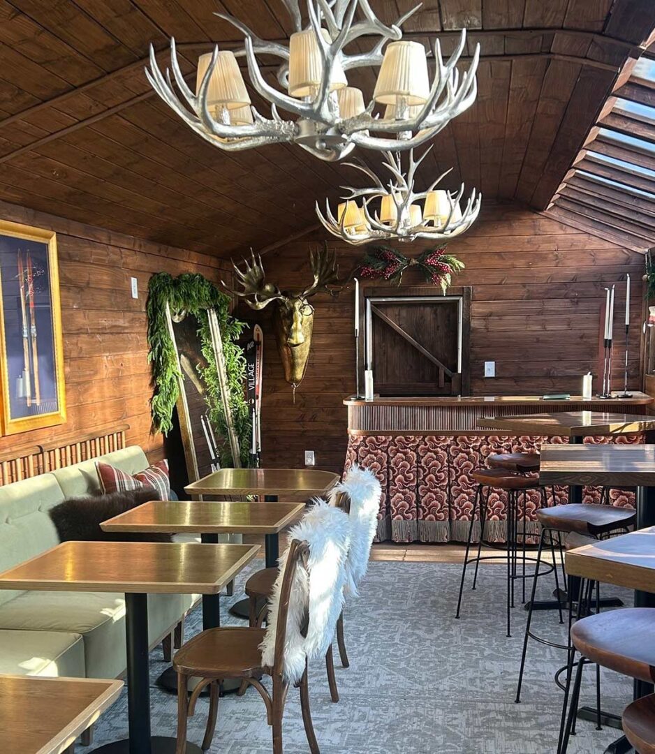 Daytime shot of a dining room in a Nordic Lodge featuring antler chandeliers.