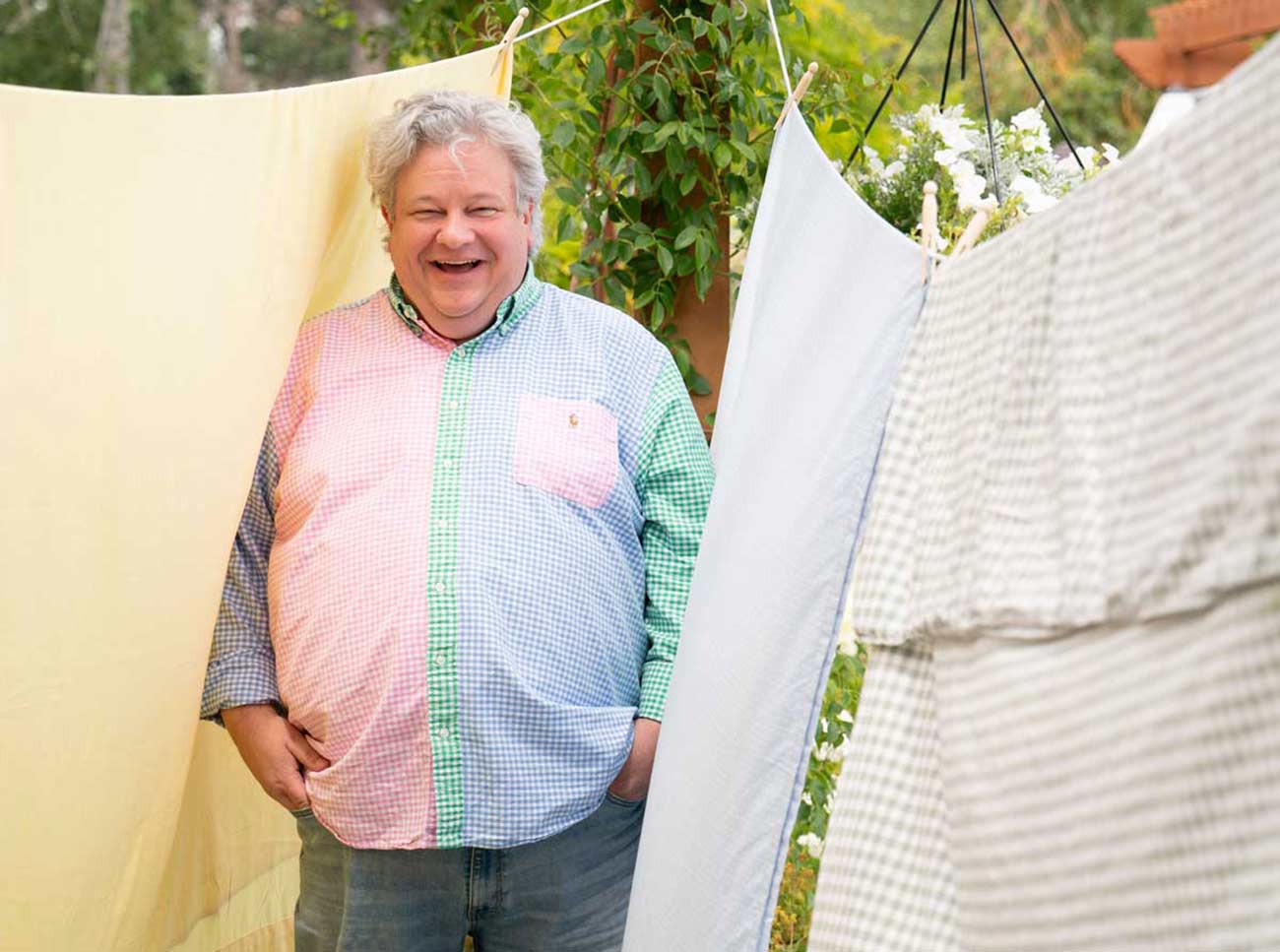 Laundry Evangelist Patric Richardson smiling next to laundry sheets drying on lines outside.