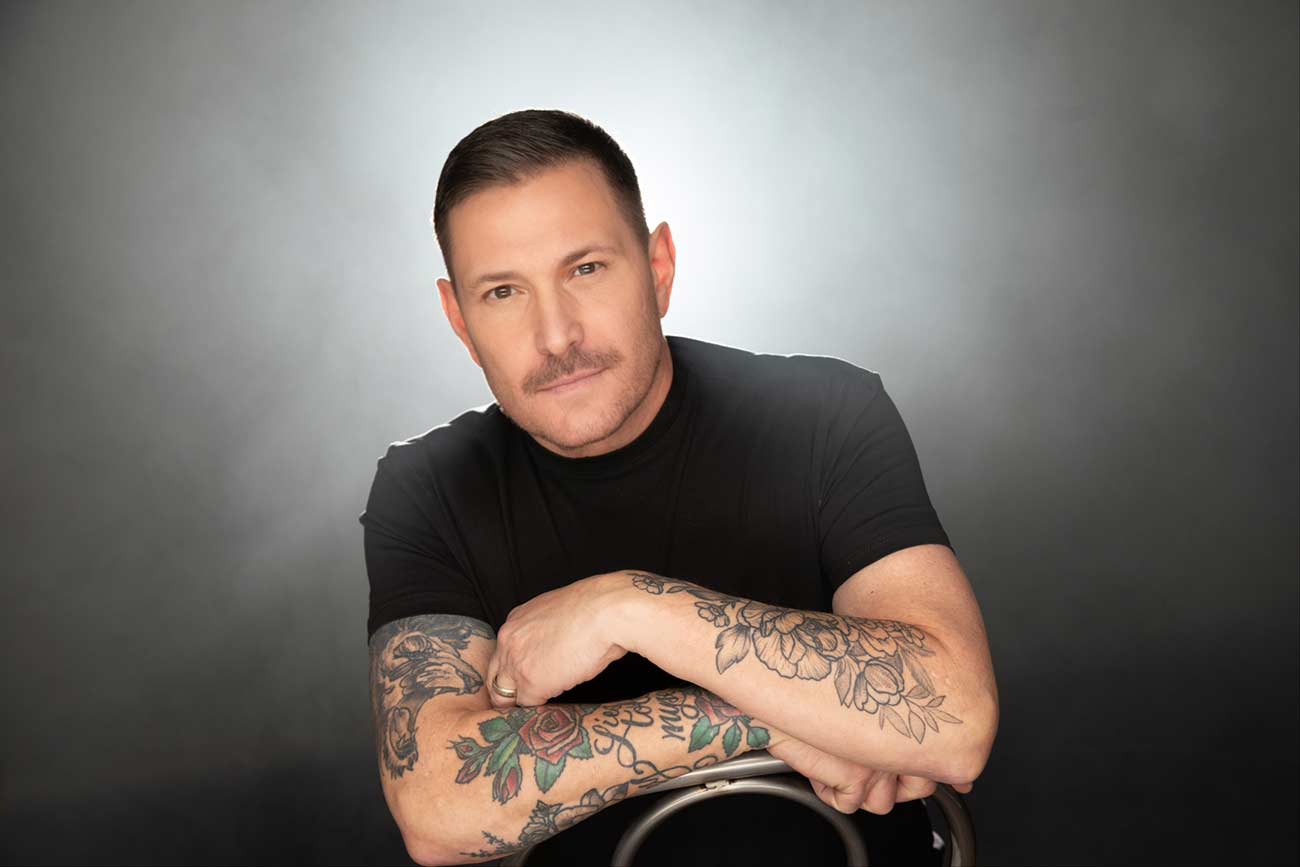 Casual shot of Ty Herndon leaning of the back of a chair.