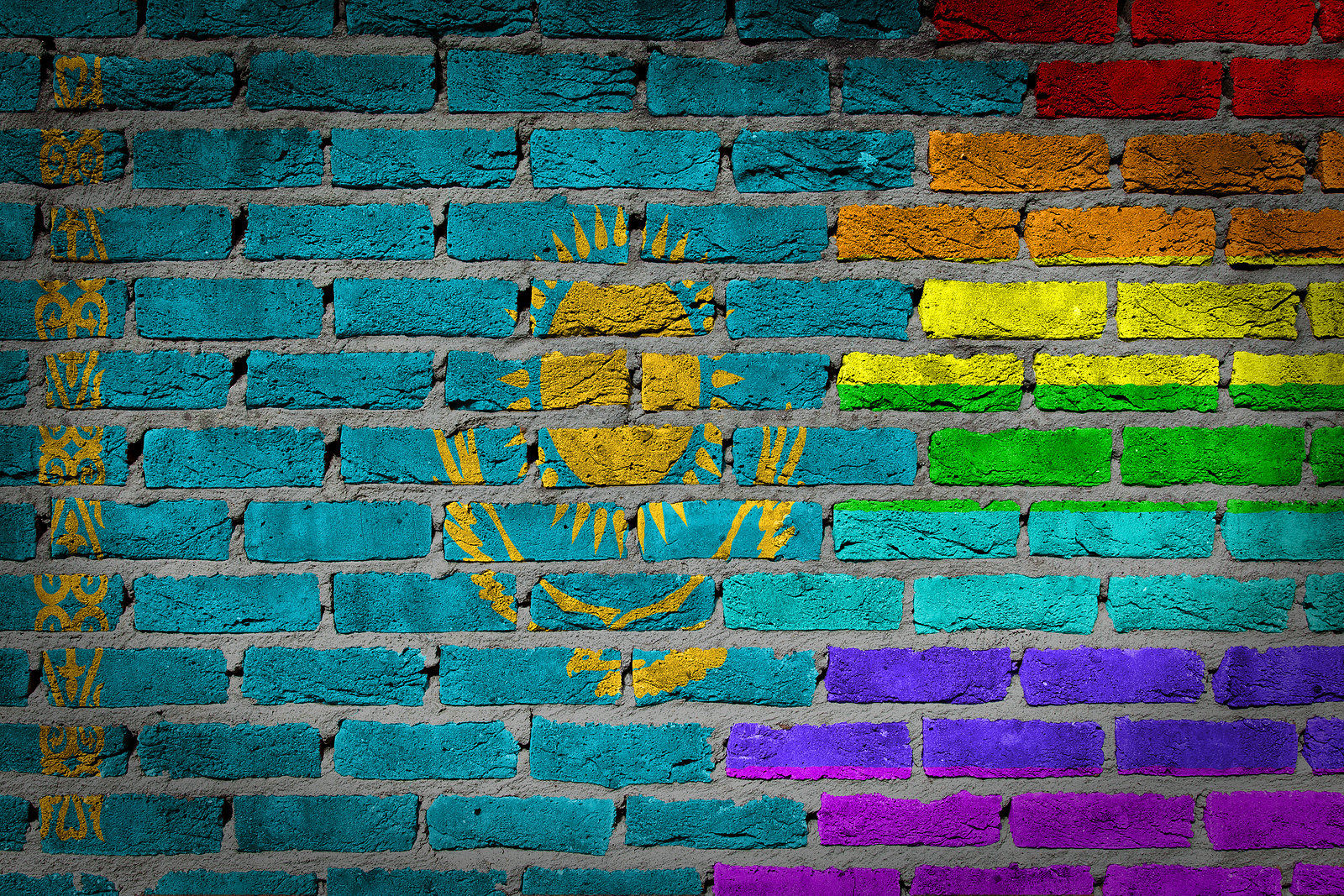 Flag of Kazakhstan covering a rainbow flag on a grungy brick wall.
