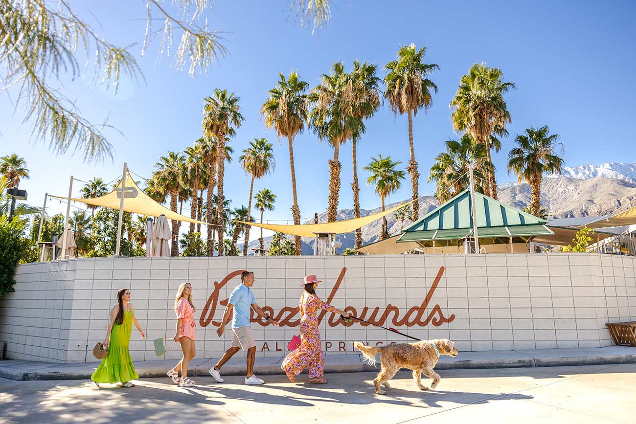 Woman walking her dog with three friends by the restaurant Boozehounds.