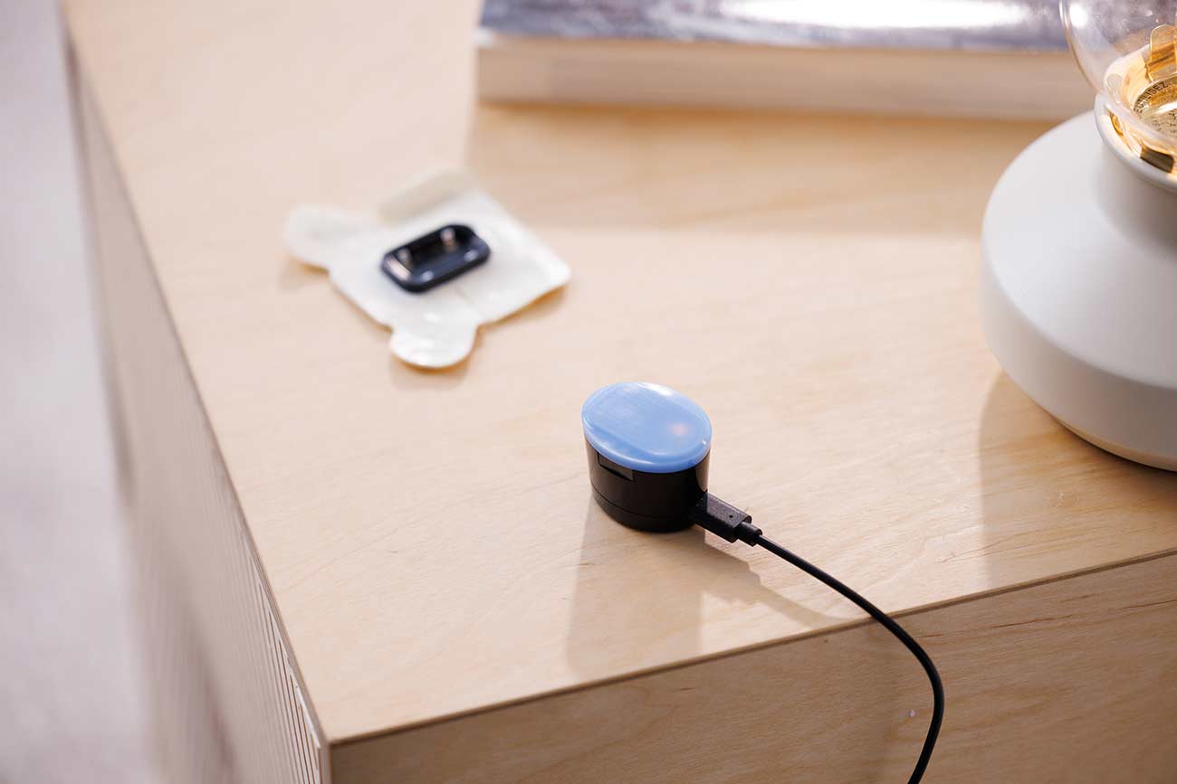 MOR charging unit and patch sitting on a night stand.