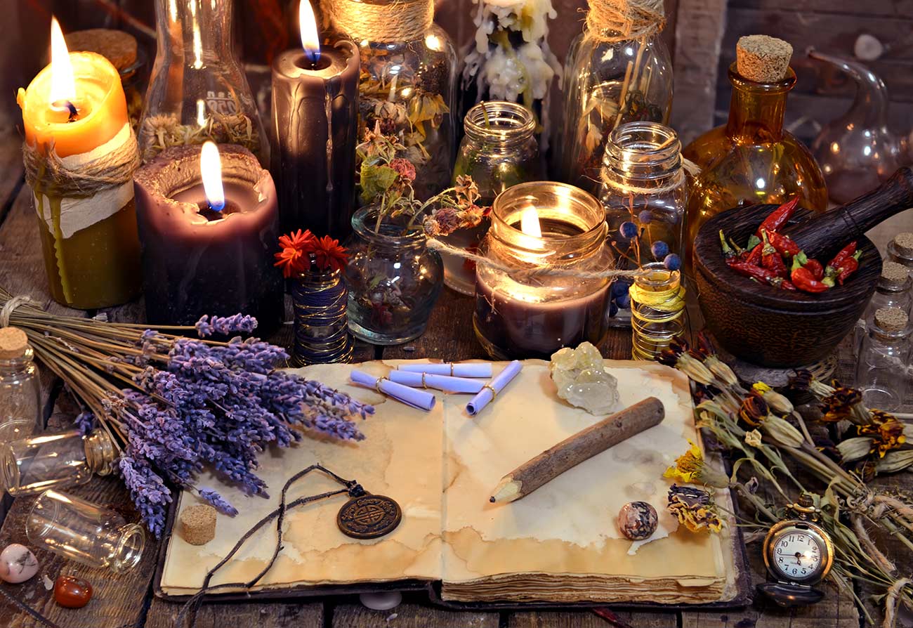 Open book with healing herbs, lavender flowers, candles, potion bottles and magic objects.