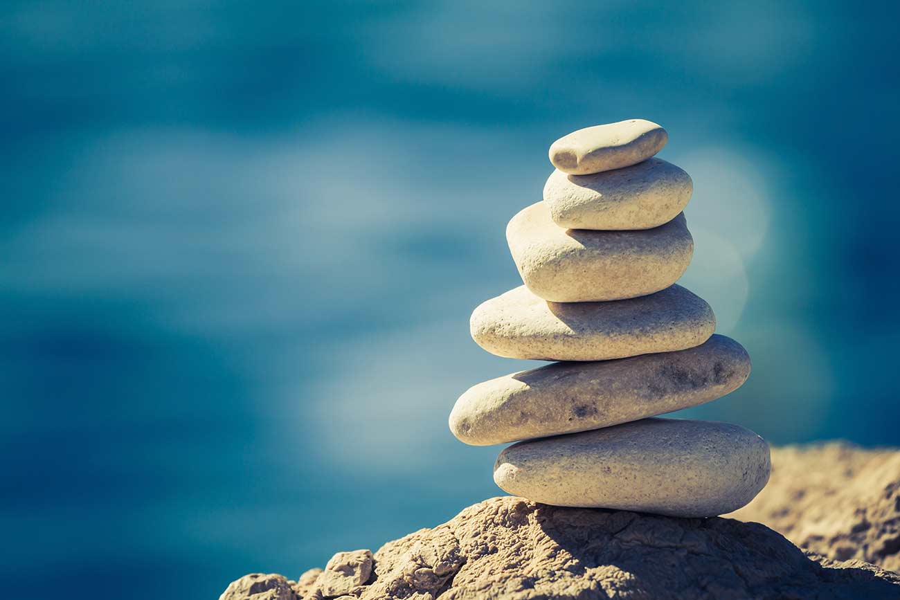 Close-up of white pebbles stack over blue sea.