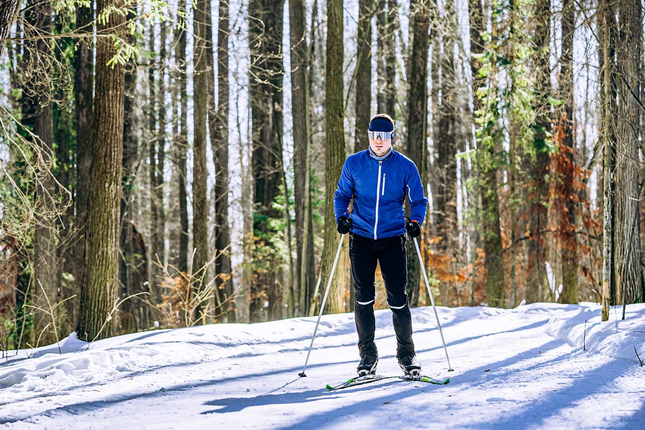 Male skiier on a trail in a wooded area.