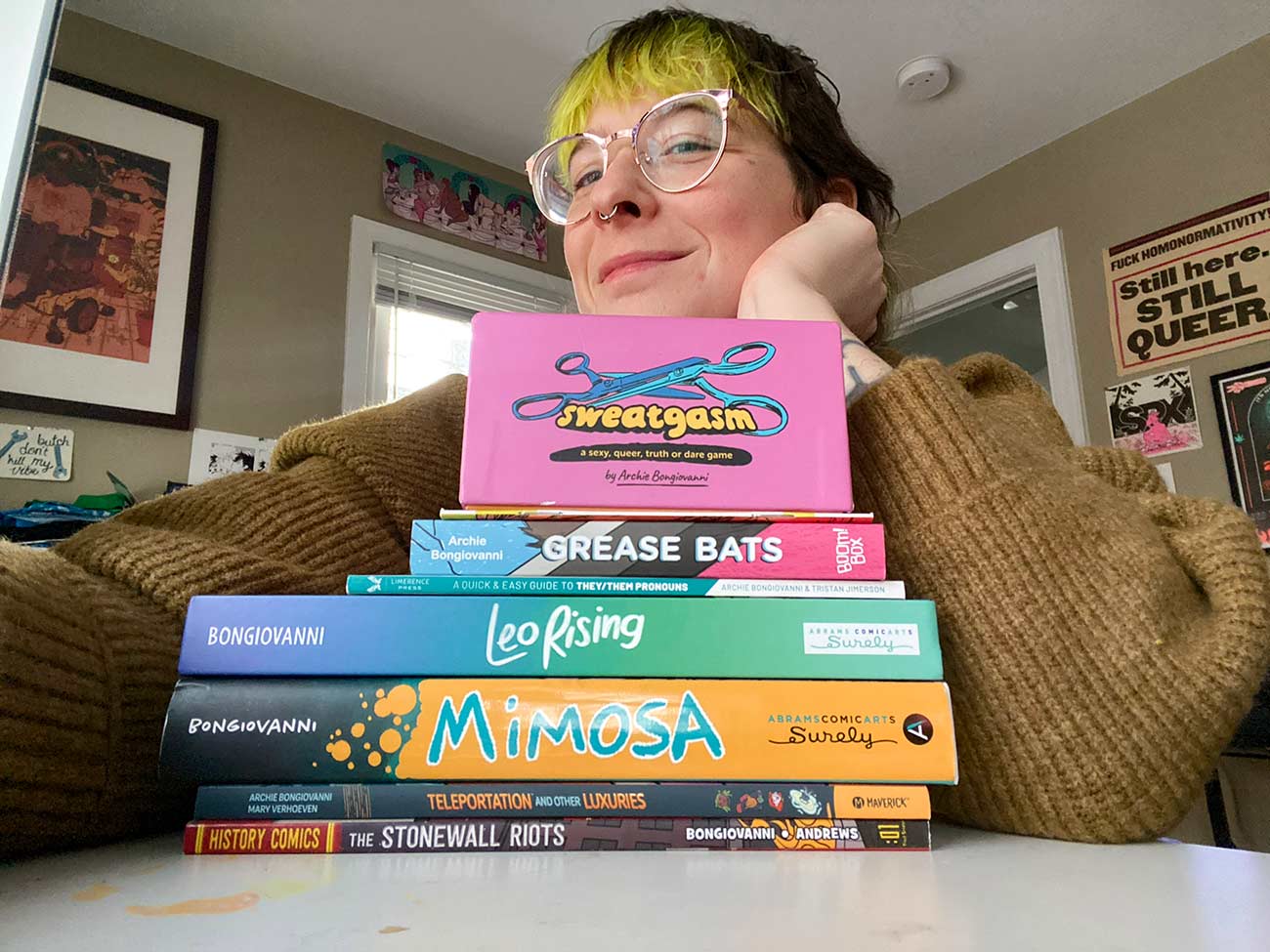 Leo Rising author Archie Bongiovanni poses with a stack of books.