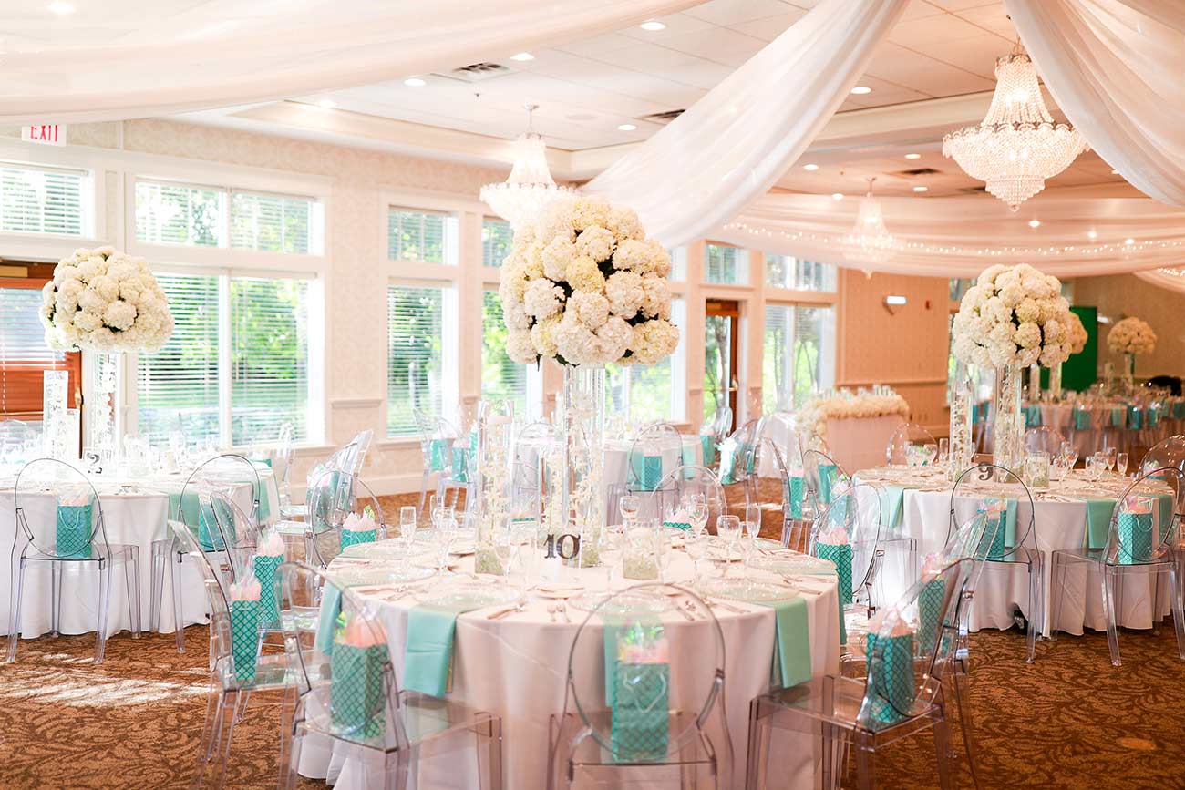 Elegant wedding tables with tall vase of flowers in the ballroom at Bearpath Golf & Country Club.