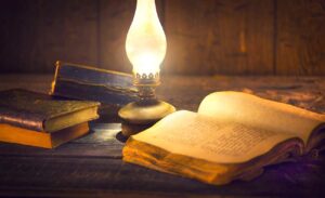 Vintage kerosene lantern and open old book with blank pages on wooden table.