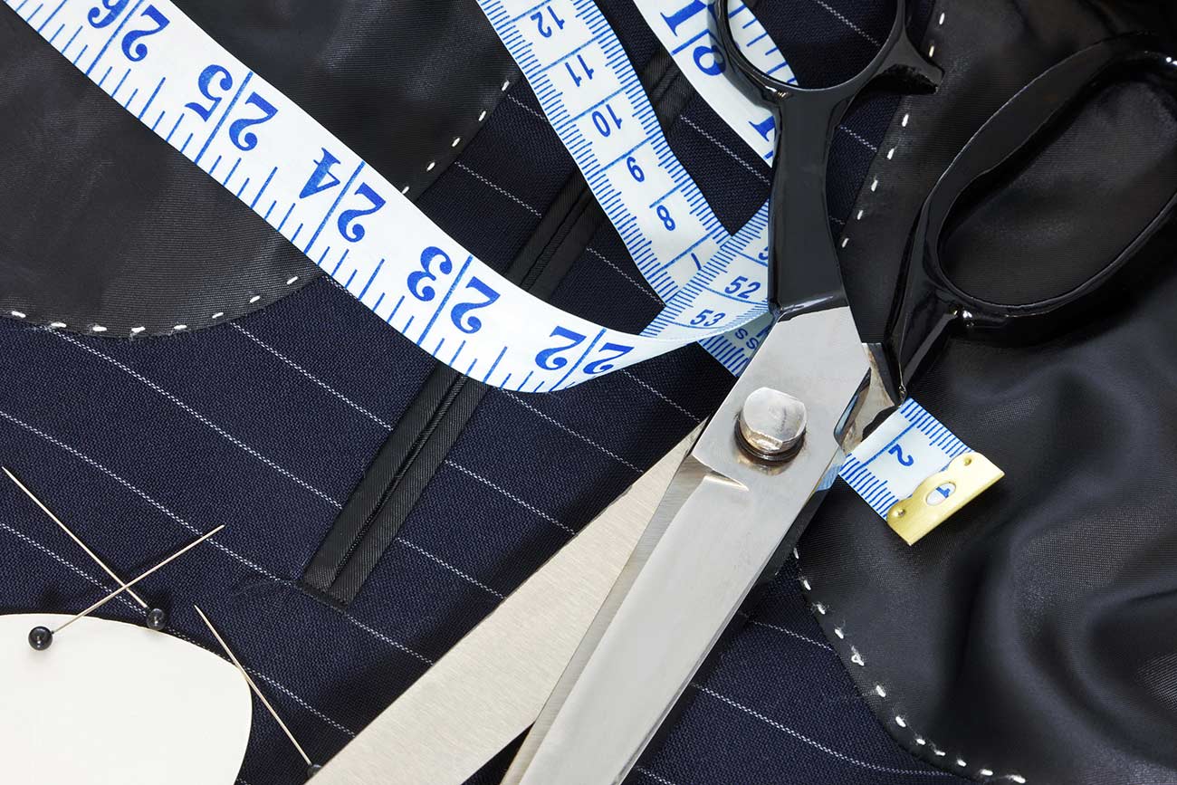 Inside of a bespoke suit jacket with hand stitching, scissors, tape measure, chalk and pins.