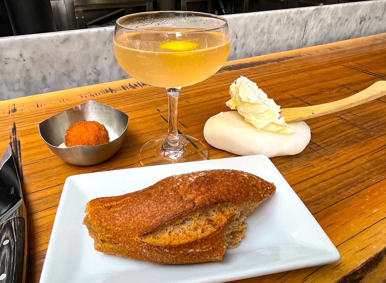 Frech 75 Cocktail with a dinner roll and black truffle arancini.
