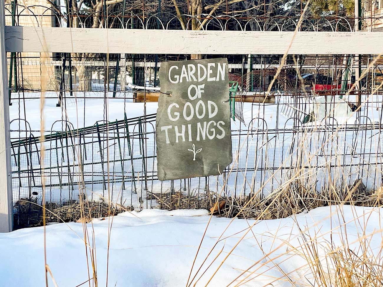 Garden of Good Things sign sits on a fence of a community garden.