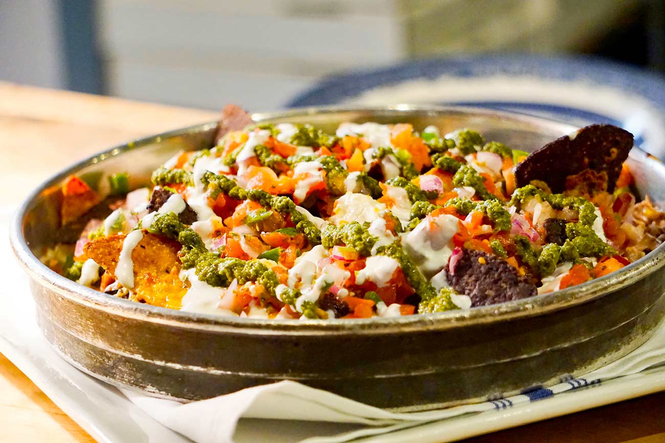 Close-up shot of a bowl of nachos with delicious toppings.