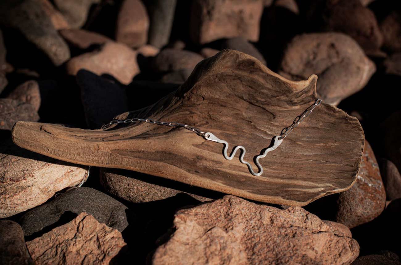 A necklace displayed on a piece of driftwood.
