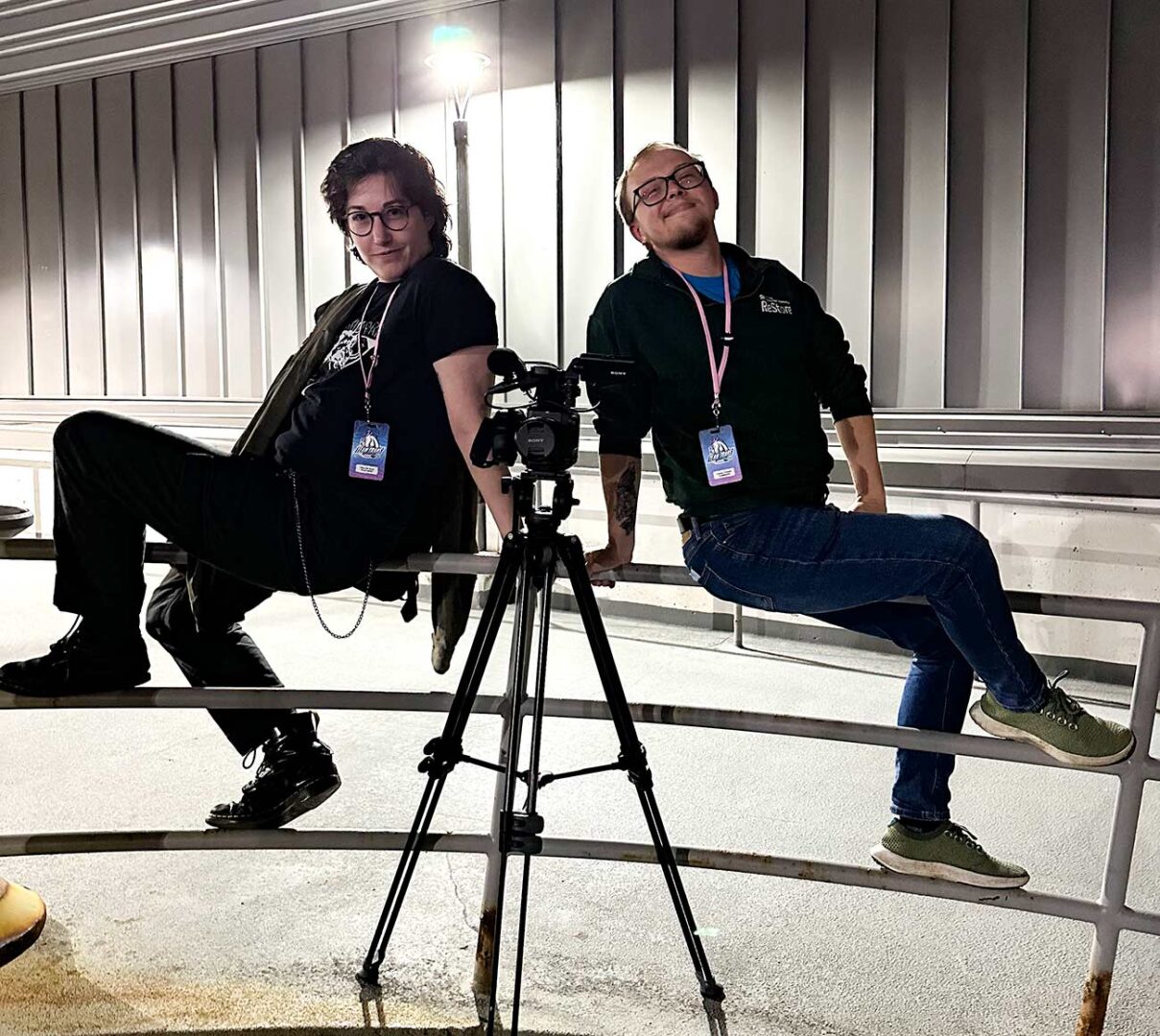 Crew members sitting on the railing with the film camera between them.