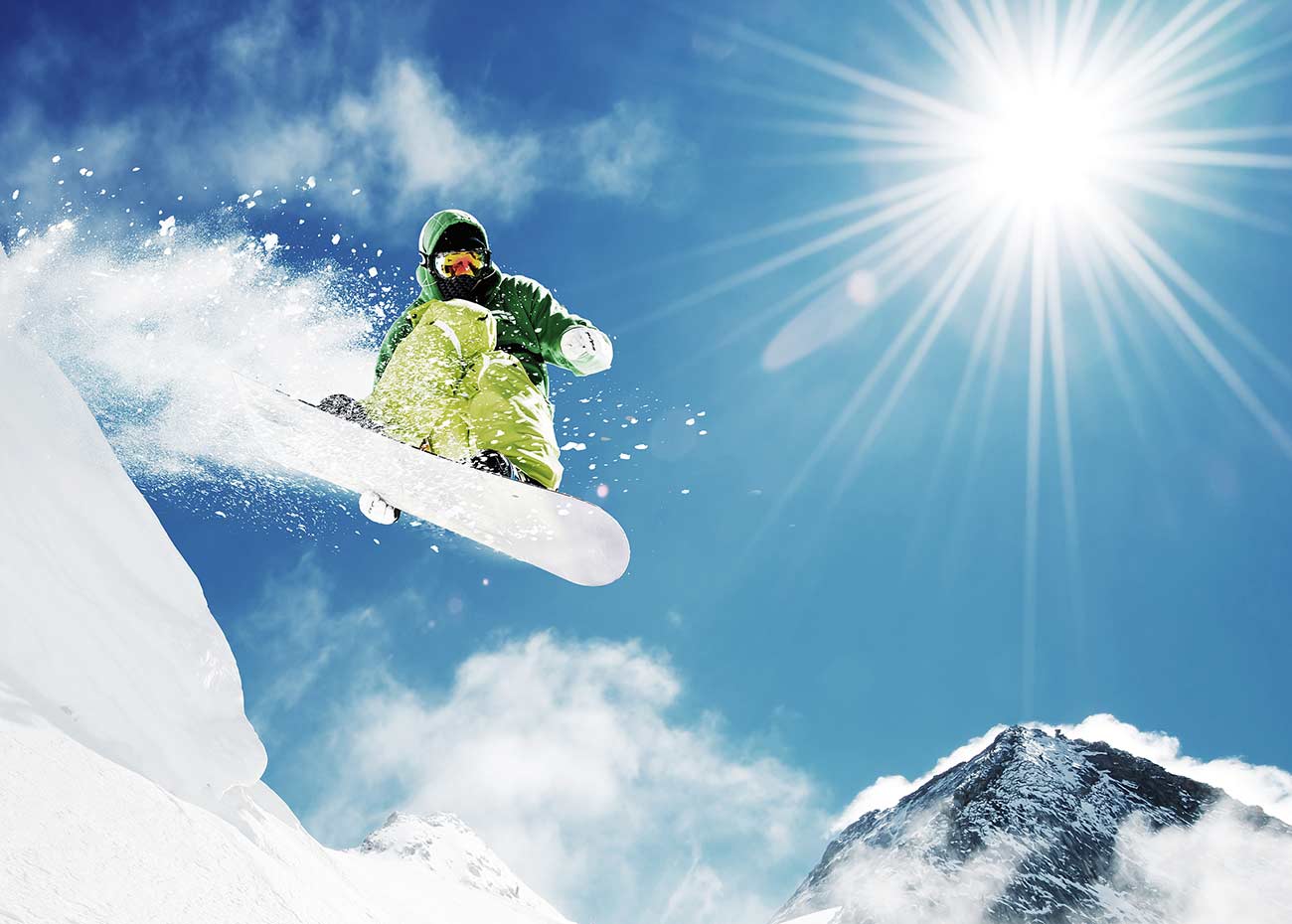 Snowboarder at jump inhigh mountains at sunny day.