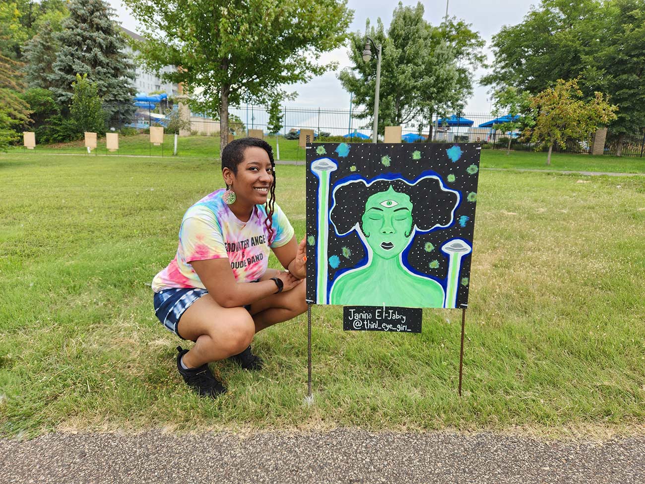 Artist Nina El-Jabry poses next to her eyeball painting.