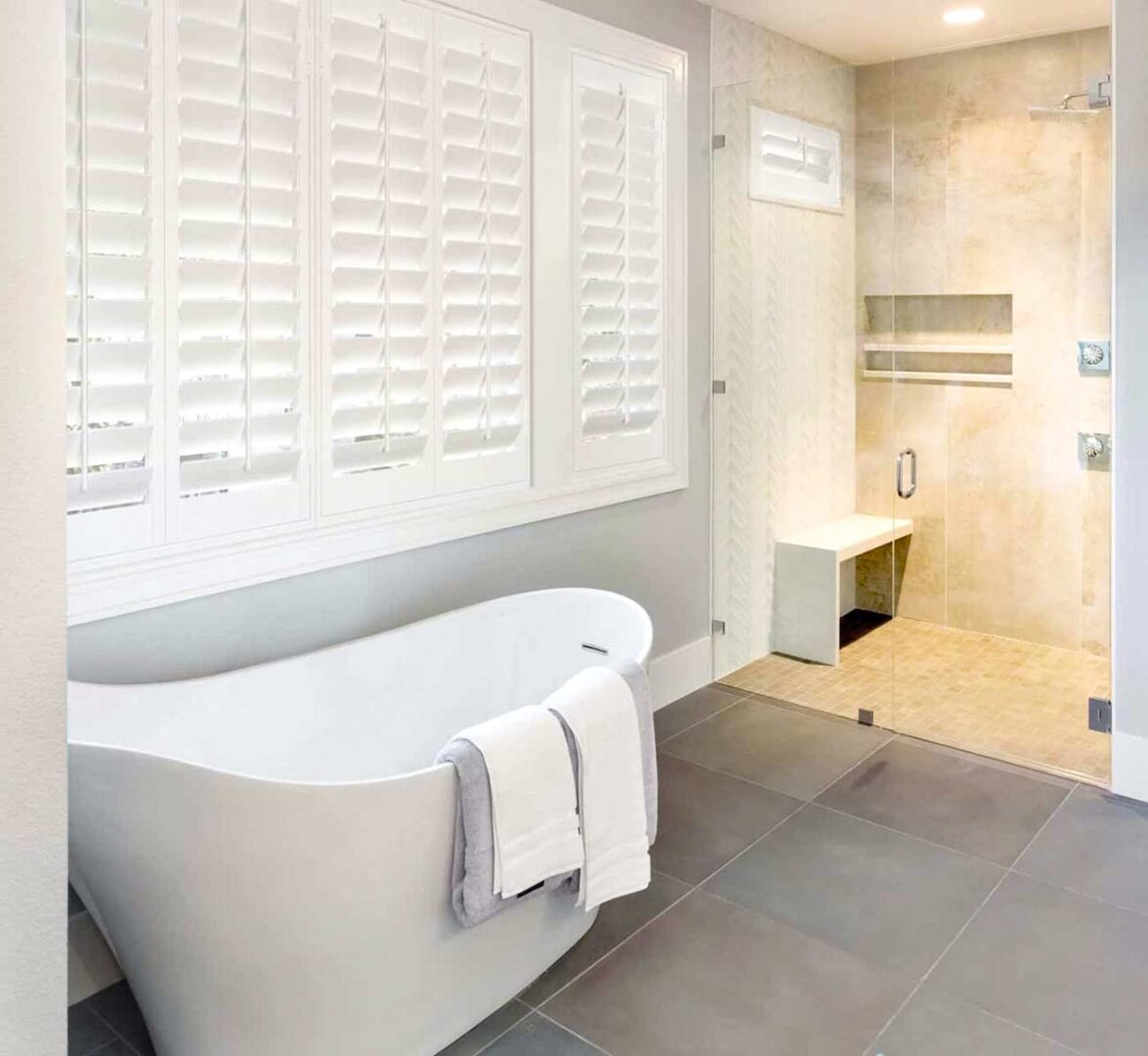 Modern bathroom with white shutters located above the bathtub.