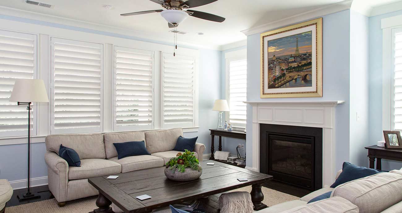 Modern living room that features white shutters on all windows.