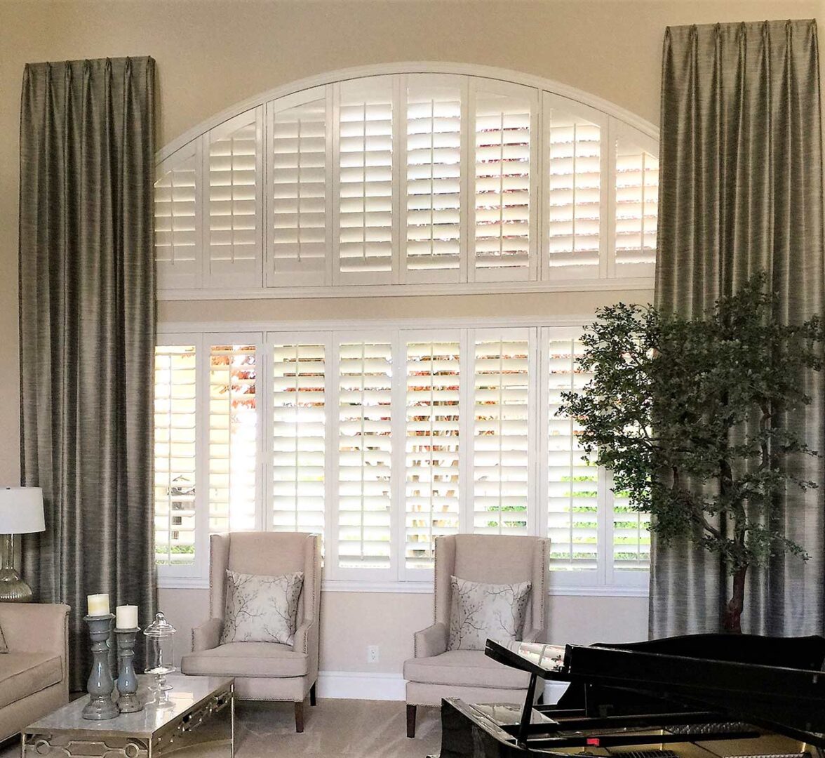 Formal living area with arch windows with multiple white shutters.