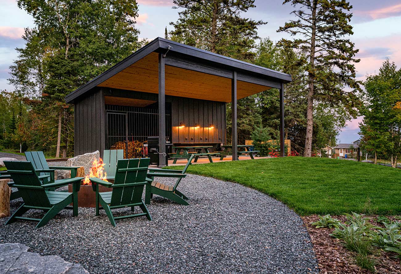 Outdoor pavilion with seating area along with a campfire seating area close by.