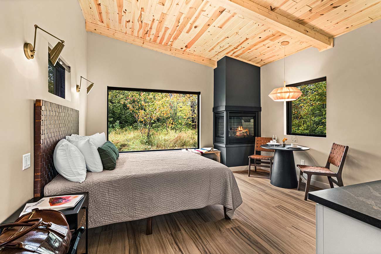 Cabin interior showing the bed, fireplace and small dining area.