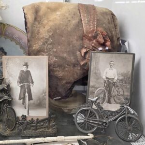 Small table of vintage black and white photos, clothing and small knick-knacks.